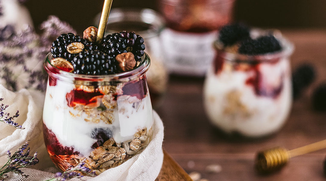 Jars filled with oats, yogurt and fruit on a wooden table.